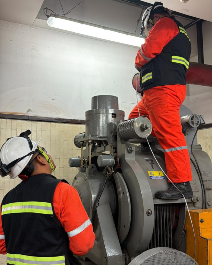 Dos personas una abajo y otro arriba de la maquinaria